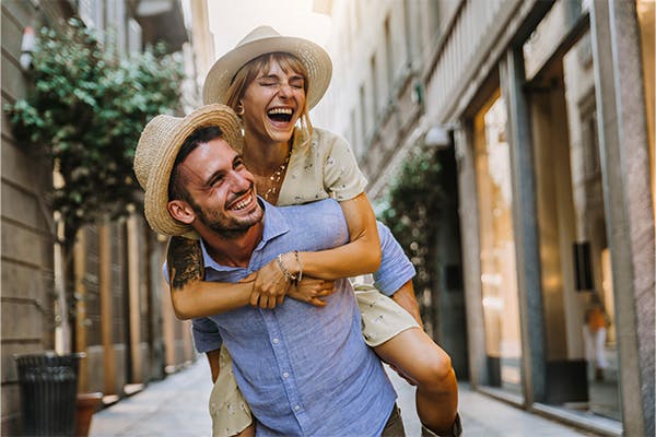 Couple-of-tourists-having-fun-walking-on-city-street-at-holiday---Happy-friends-laughing-together-on-vacation---People-and-holidays-concept
